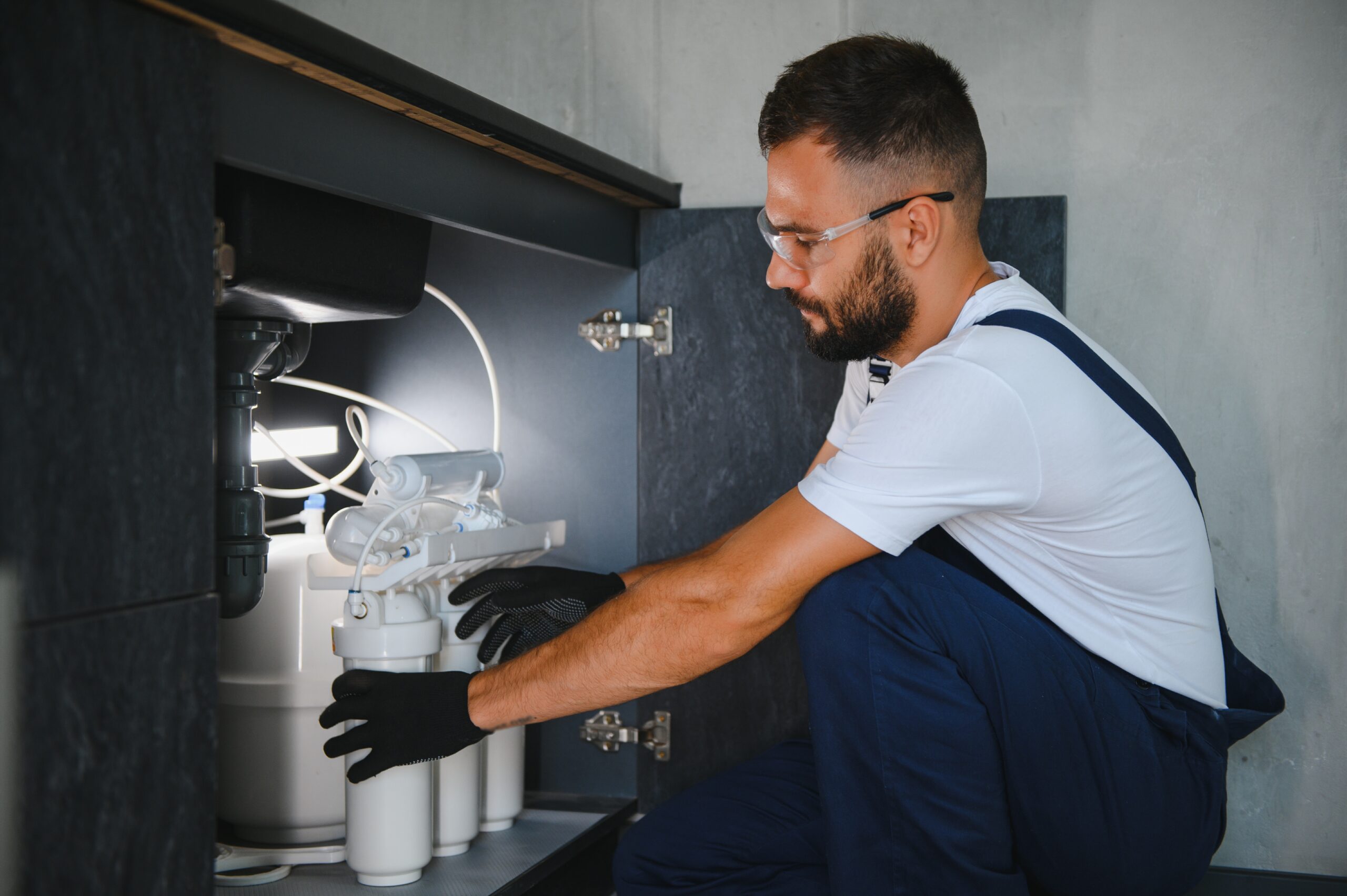 Homeowner installing new water filter under a kitchen sink